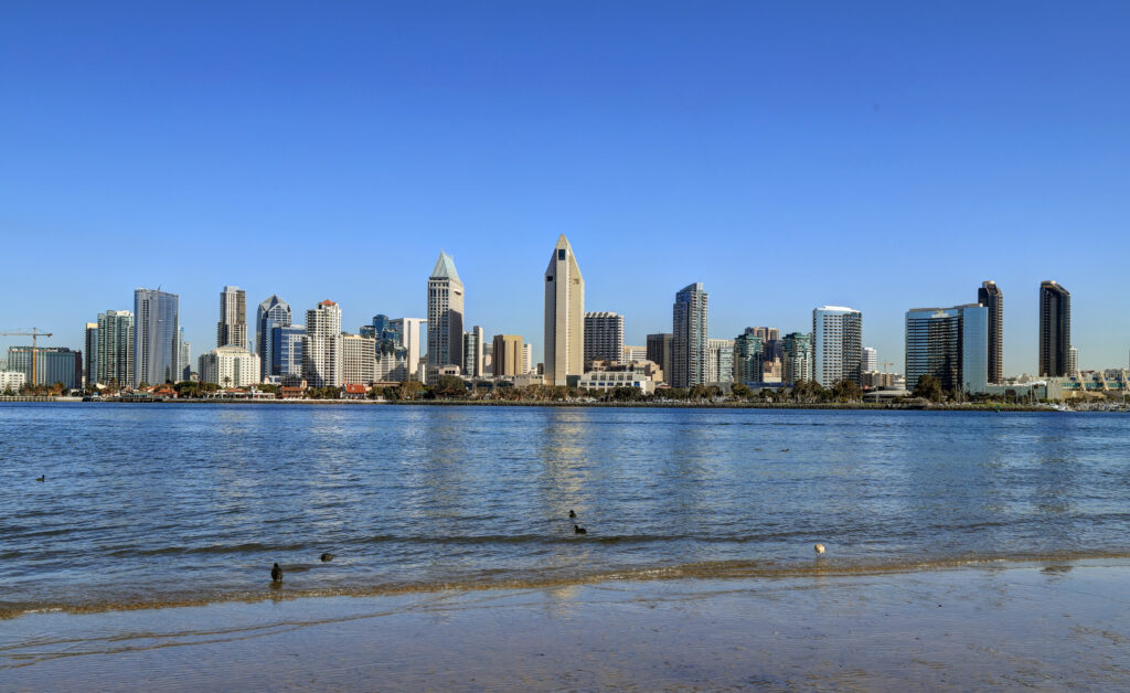 A daytime view of the San Diego city skyline from across a beach.